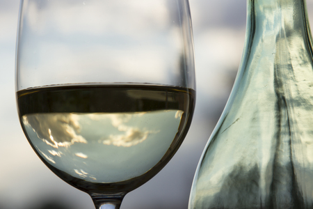 A glass of white wine and a bottleの写真素材
