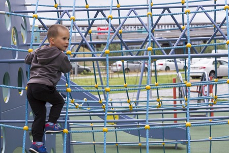 little boy playing on playground in summer outdoor parkの写真素材