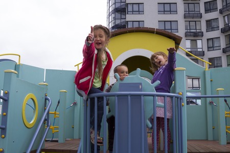 Three little children climbing ladder and looking at cameraの写真素材