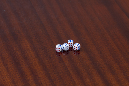 Photo of four white dices being stacked up on wooden backgroundの写真素材