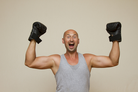 man in boxing gloves rejoices victory over gray backgroundの写真素材