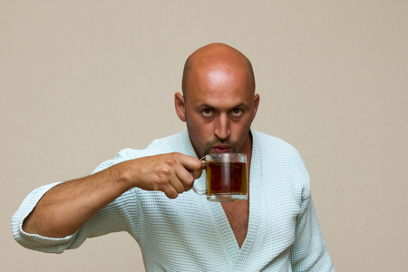 A man in a blue bathrobe with tea. baldの写真素材