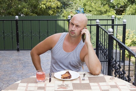 Man talking on the phone while eatingの写真素材