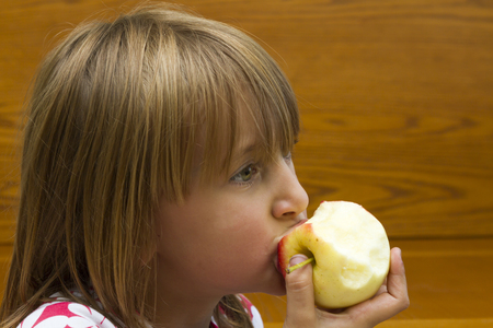 little girl eating an appleの写真素材