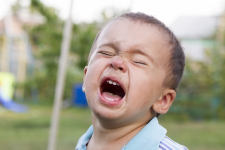 Angry, sad and unhappy baby child. shouting and crying. problem child with head in hands. concept for bullying, depression stresの写真素材