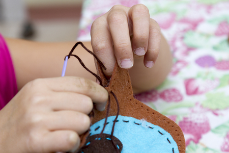 happy cute little girl is engaged in sewingの写真素材