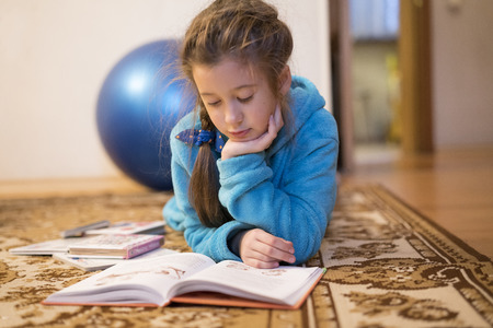 Portrait of 7 years old child reading book at home