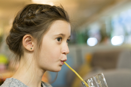 Cute little girl drinks from the strawの写真素材