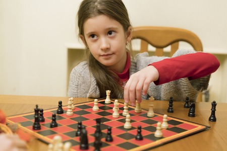 Young caucasian girl with long hair playing a game of chess.の写真素材
