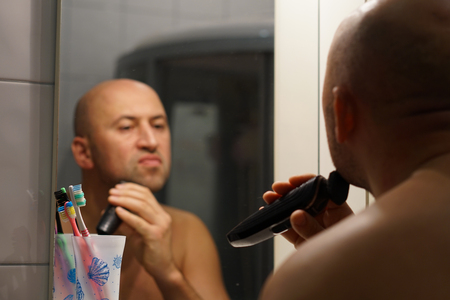 Young man shaving his beard with a razor, close upの写真素材