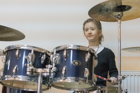 Happy girl in music therapy by playing drum kit on music roomの写真素材