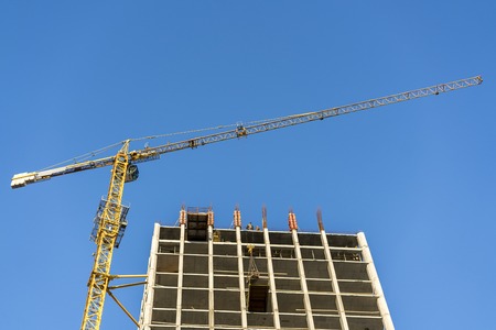 Construction of a high-rise building. Crane, builders against the blue skyの写真素材