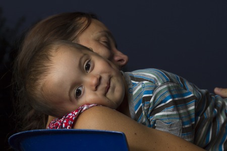 Happy mother with baby boy in her arms against the background of the evening skyの写真素材