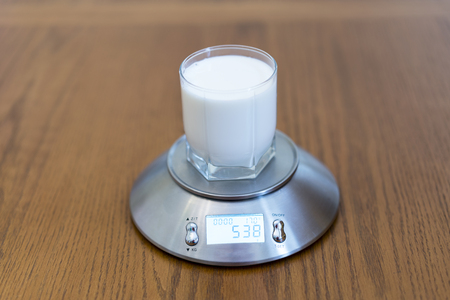 A glass of milk on the scalesの写真素材