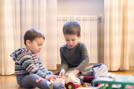 Two little brothers play in the playing room with an ambulanceの写真素材