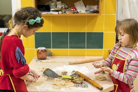 Two sisters 5 and 7 years in the kitchen make pastry cookies. Two moms assistant.の写真素材