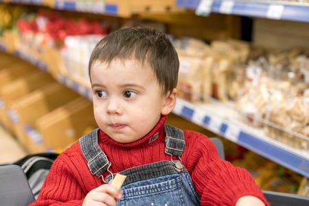 Boy 2 years in a store on the background of breadの写真素材