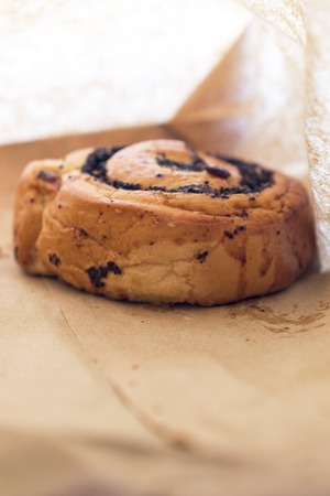 Fresh appetizing bun with poppy seeds in a paper bag.の写真素材