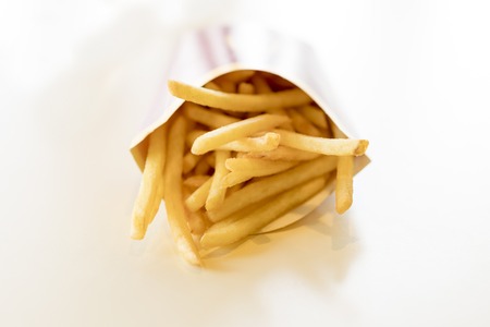 French fries in a box on a light background. Unhealthy food. Delicious food.