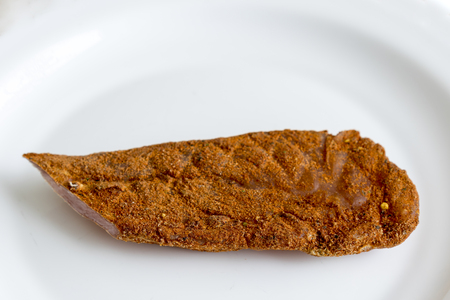A piece of meat with spices on a white plate.の写真素材