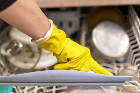 Woman puts dishes in the dishwasher.の写真素材