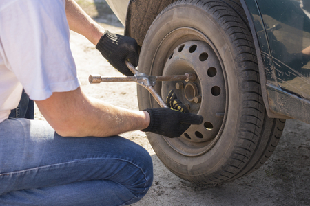 Mechanic changing wheel on car with a wrenchの写真素材