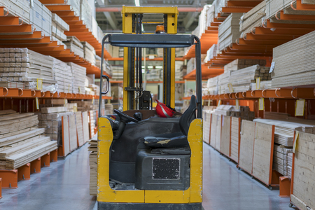 Warehouse with variety of timber for construction and repair. Delivery concept. timber warehouse - shelves with wooden planks and forkliftの写真素材