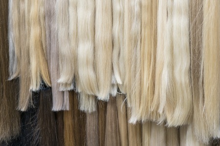 Close up brown, white and another color of hair wigs display in beauty salon. Premium different color clip-in hair extensions displayed in wig shop.の写真素材