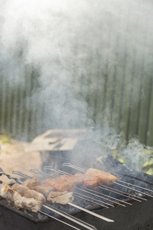 cooking meat and potatoes on skewers in a barbecue with smoke.の写真素材