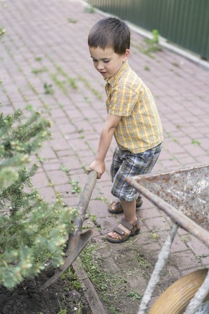 Little boy with a big shovel. little happy boy working with shovel in garden. boy 5 years old keeping a big shovelの写真素材