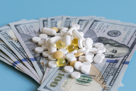 dollars pills medicine. Prescription medicine on dollars for pharmaceutical industry concept of high cost for healthcare and medication, top down viewの写真素材
