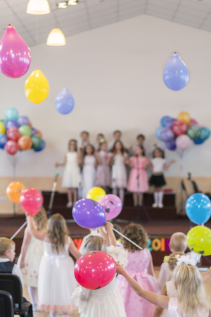 Children's holiday in kindergarten. Children on stage perform in front of parents. image of blur kid 's show on stage at school , for background usage. Blurry. Balloons.の写真素材