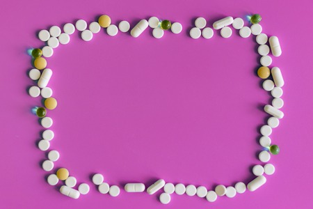 Frame of pills on a pink background. Pills for design. Concept of health, healthy lifestyle. Copy space for advertisementの写真素材