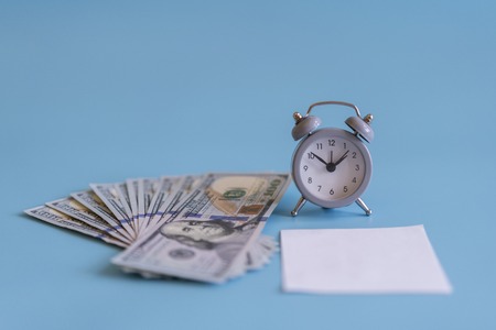 Alarm clock and dollars, close up. Time is money. Gray alarm clock on money banknotes Dollars, concept of business planning and finance. Place for your inscription.の写真素材