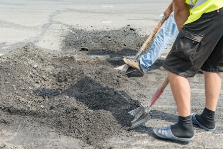 Workers and machinery are working paved road with asphalt and gravel, Street construction for land transportation, Road repair works.の写真素材