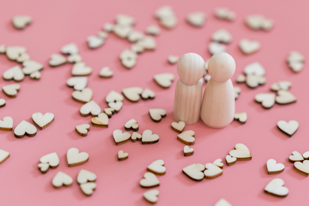 the concept of a loving couple. A happy couple in love. Two wooden figures and hearts on a pink backgroundの写真素材