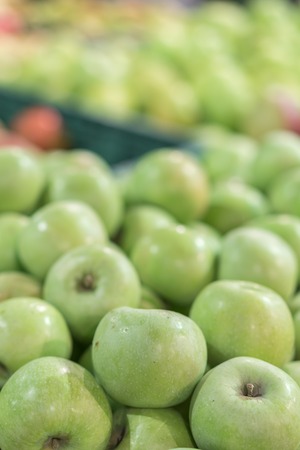 Green apples in a box in the store. green apples in boxes on market shelves. grocery shopping concept. healthy food. vertical photo.の写真素材
