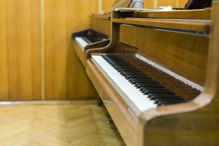 Two brown pianos in the music class. Close up of piano keys at classroom.の写真素材
