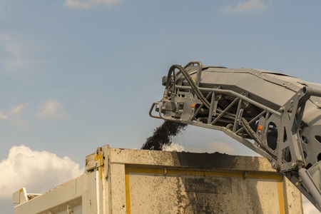 loading road debris in the car. A heavy tractor removes the old asphalt and loads the debris into the car. tonedの写真素材
