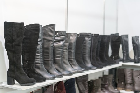 women's boots on the shelves in the store. Pavilion of the store with fashionable women's shoes. Leather autumn-winter bootsの写真素材