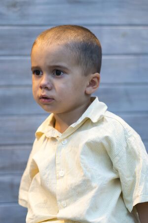 Beautiful little boy 2 years on a gray background. vertical photo