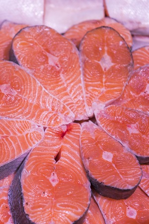 Sliced raw, not cooked salmon, red fish, lying in the ice on the counter in the supermarket. Fresh fish. The big pieces of red fish on ice in the fish market. vertical photo.の写真素材