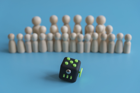 Crowd calm concept. answer how to calm the crowd. Fidget Cube stress reliever and wooden figures on a blue background.の写真素材