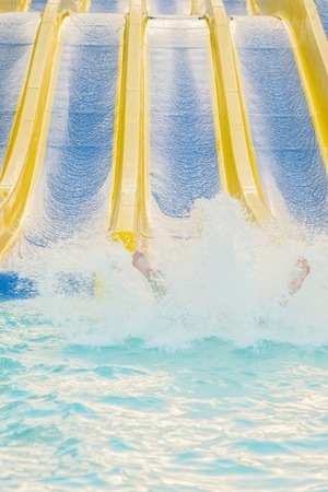 girl sliding water park. Woman sliding down on water-slide in aqua park. vertical photoの写真素材