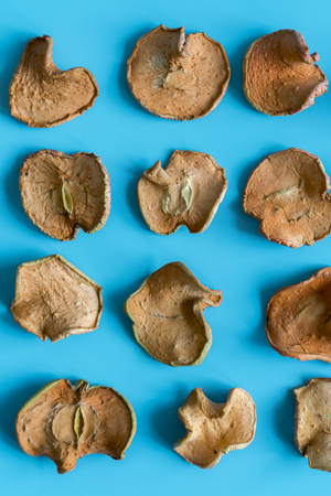 slices of dried apple on blue background. Shallow depth of field. Homemade sun-dried organic apple...