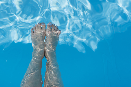 Closeup of beautiful female legs in water of a pool. Legs in the pool. Vacation at summer.の写真素材