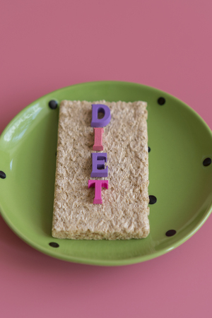crunchy loaves of bread and a glass of water the inscription deet on a pink background. Concept of losing weight and healthy lifestyle. vertical photo.の写真素材