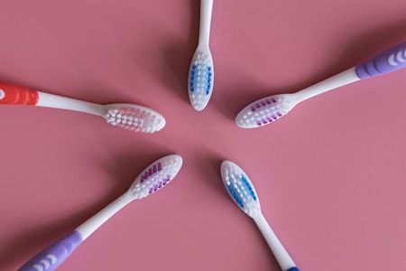 Toothbrushes on pink background. Flat lay composition with manual toothbrushes on color background,...