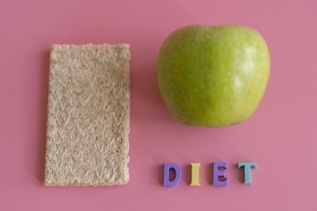crunchy loaves of bread and Apple the inscription diet on a pink background. Concept of losing...
