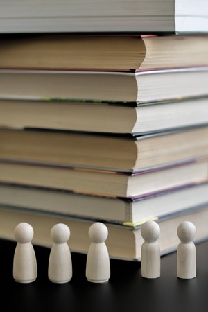 Figures of people and a stack of books on a black background. The concept of education. The problem...